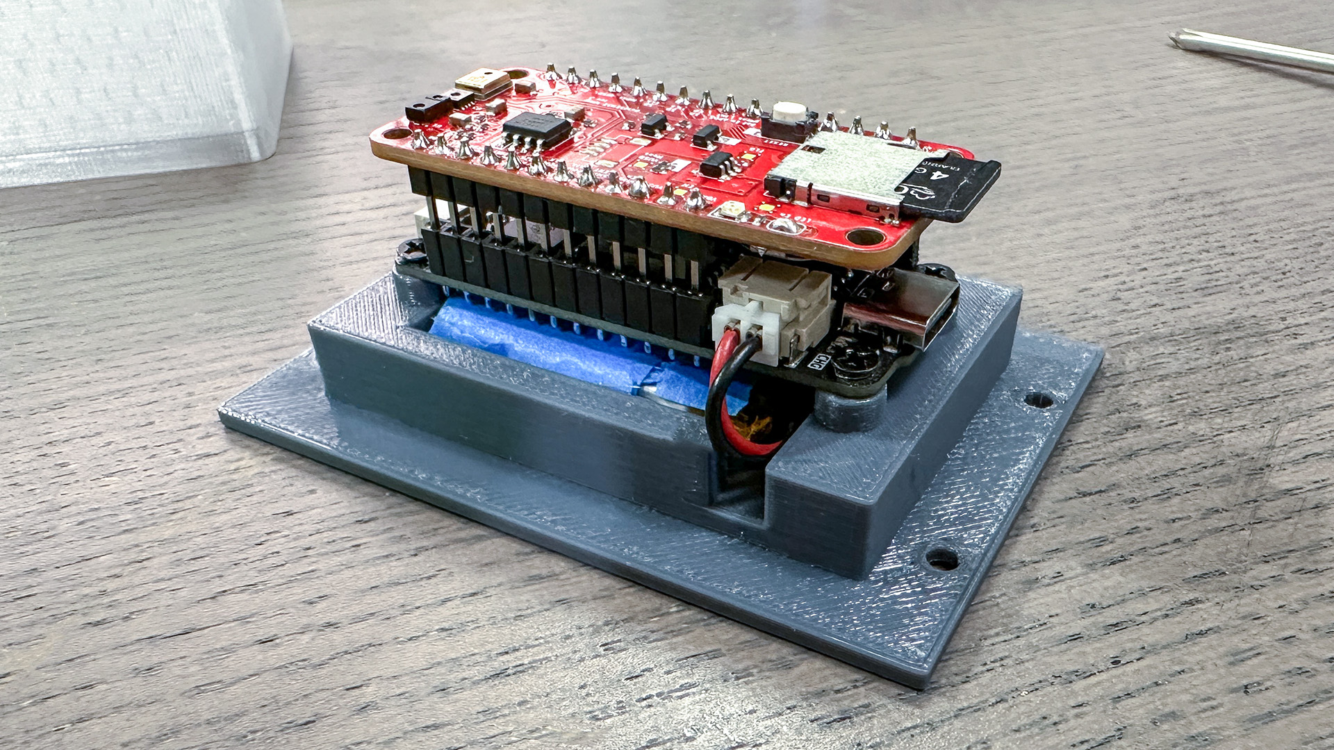 Completed Bald SENSE board stack with a battery and microSD card mounted in a 3D-printed enclosure.